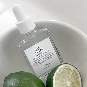 Skin TOGO Dr. Althea Natural Radiance Essence serum bottle with a dropper, placed next to fresh lime halves.