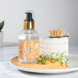 Skin TOGO Elizavecca CER-100 Hair Muscle Essence Oil in a clear pump bottle with a cartoon label on a white plate.