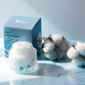 Skin TOGO Elizavecca Aqua Hyaluronic Acid Water Drop Cream jar and box with cotton flowers on a blue marble surface