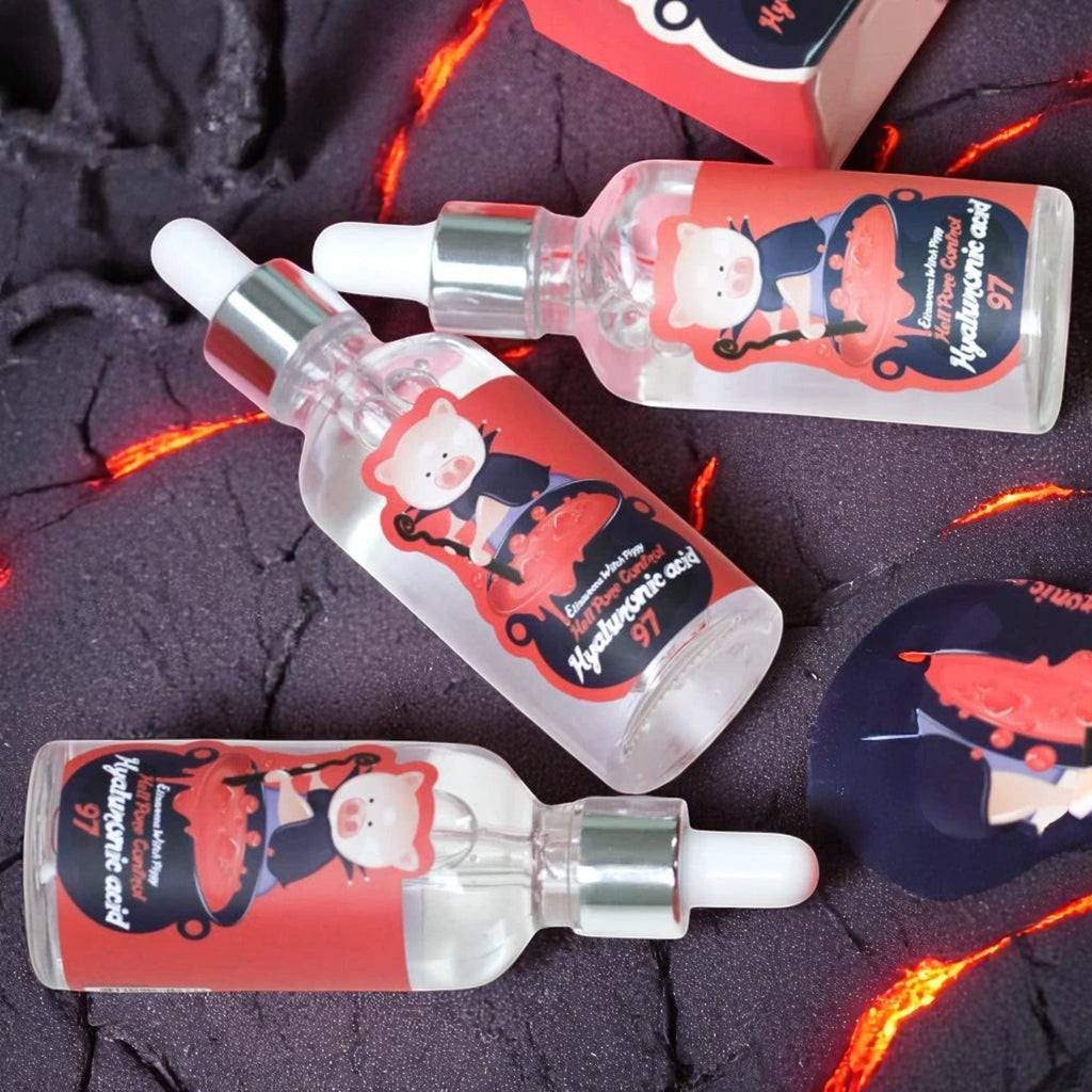 Skin TOGO Elizavecca Witch Piggy Hell Pore Control Hyaluronic Acid serum bottles on a dark volcanic background