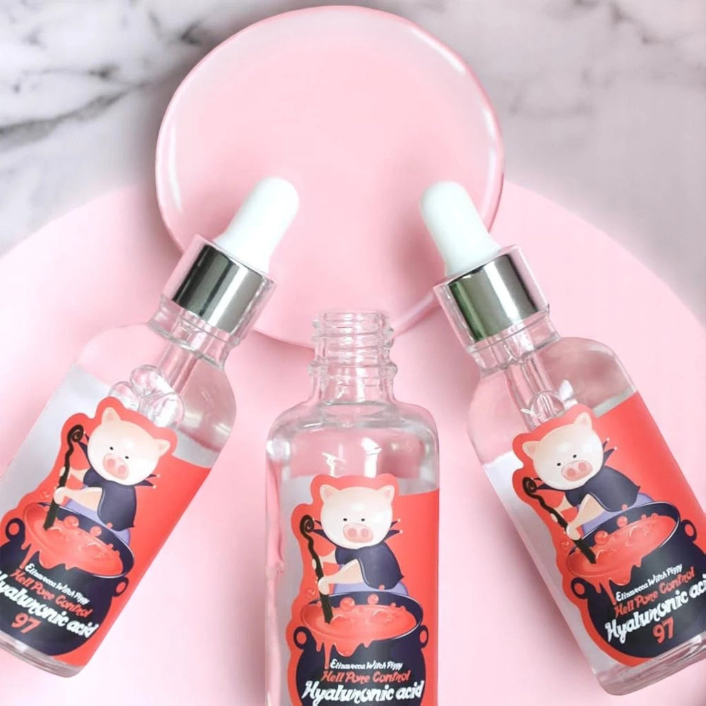 Skin TOGO Elizavecca Witch Piggy Hell Pore Control serum bottles with dropper caps on a pink circular background