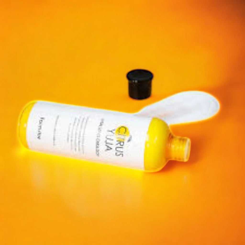 Skin TOGO Farmstay Citrus Yuja Vitalizing Emulsion bottle with yellow packaging and a black cap on an orange background