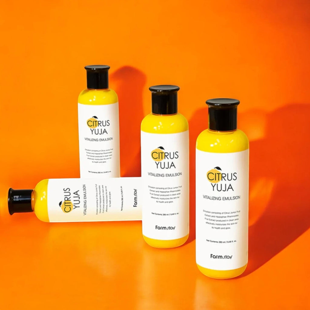Skin TOGO Farmstay Citrus Yuja Vitalizing Emulsion bottles with bright yellow packaging on an orange background