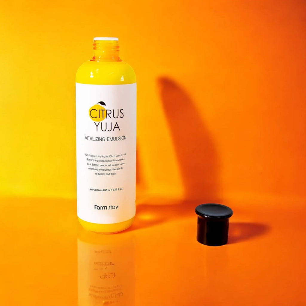 Skin TOGO Farmstay Citrus Yuja Vitalizing Emulsion bottle with a black cap on a vibrant orange background.