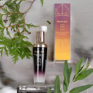 Skin TOGO Farmstay Grape Stem Cell Emulsion bottle and box with green botanical accents on a marble surface.