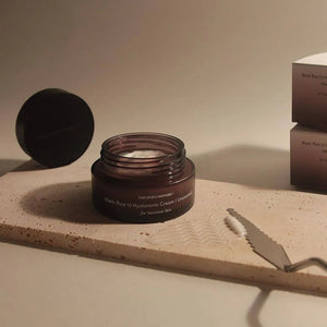Skin TOGO Haruharu WONDER Black Rice Hyaluronic Cream in a dark glass jar with a spatula on a stone tray.