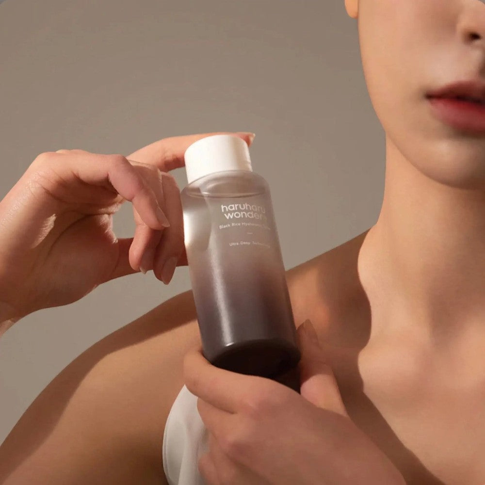Skin TOGO model holding a bottle of Haruharu WONDER Black Rice Hyaluronic Toner with a gradient design