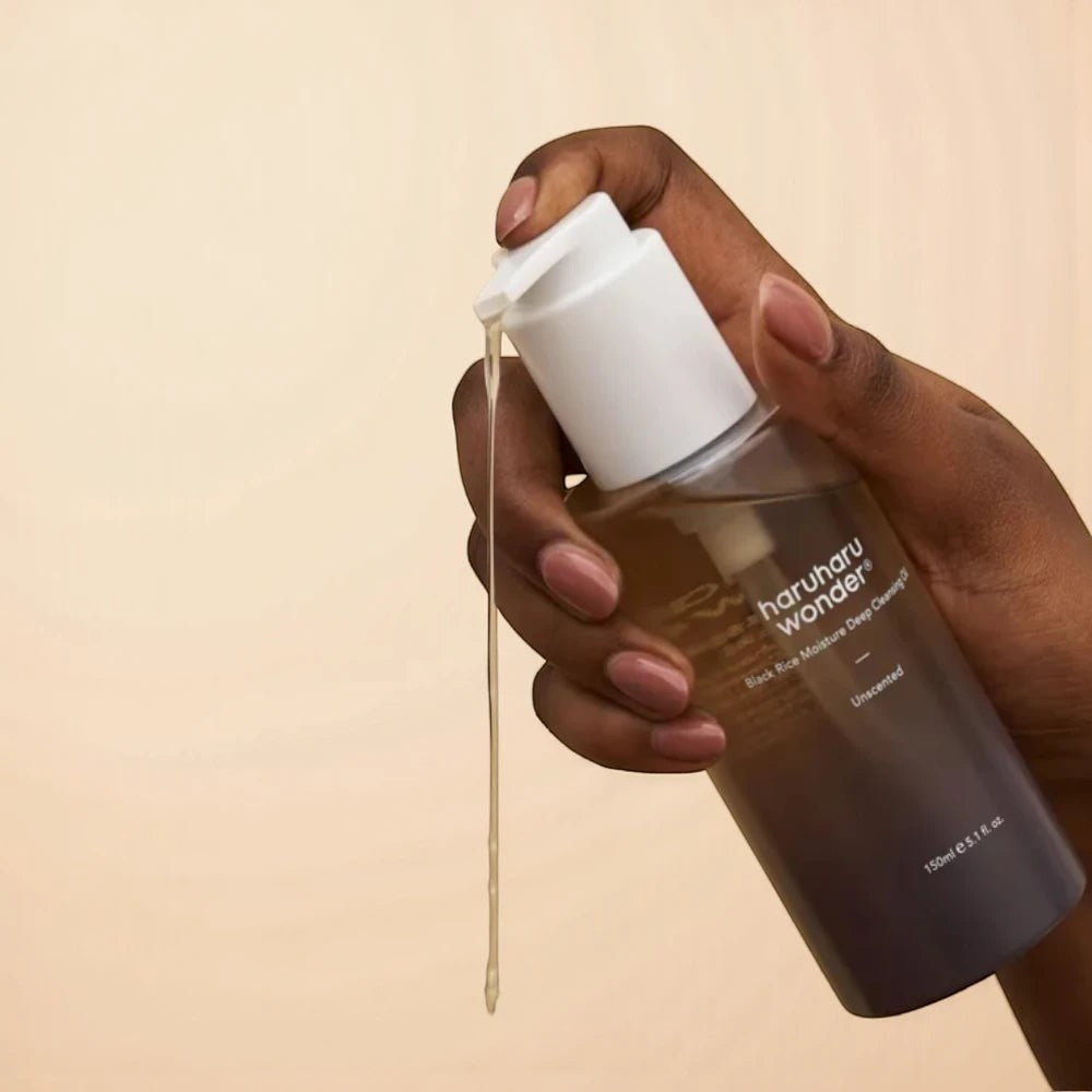 Skin TOGO Haruharu WONDER Black Rice Deep Cleansing Oil in a clear pump bottle with oil dripping from the nozzle.