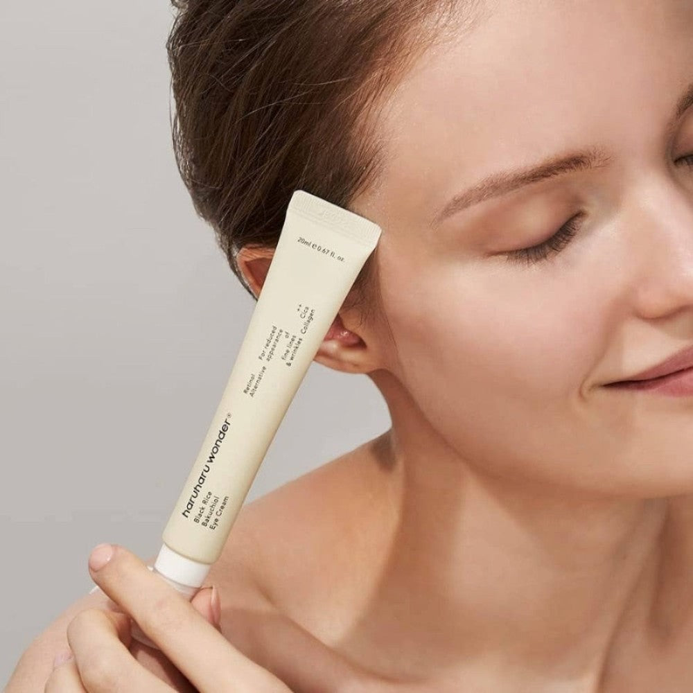 Skin TOGO model holding a tube of Haruharu WONDER Black Rice Bakuchiol Eye Cream against her temple