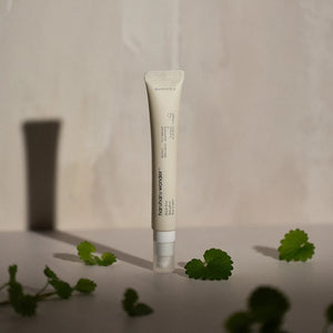 Skin TOGO Haruharu WONDER Black Rice Bakuchiol Eye Cream in a beige tube with green leaves on a neutral background