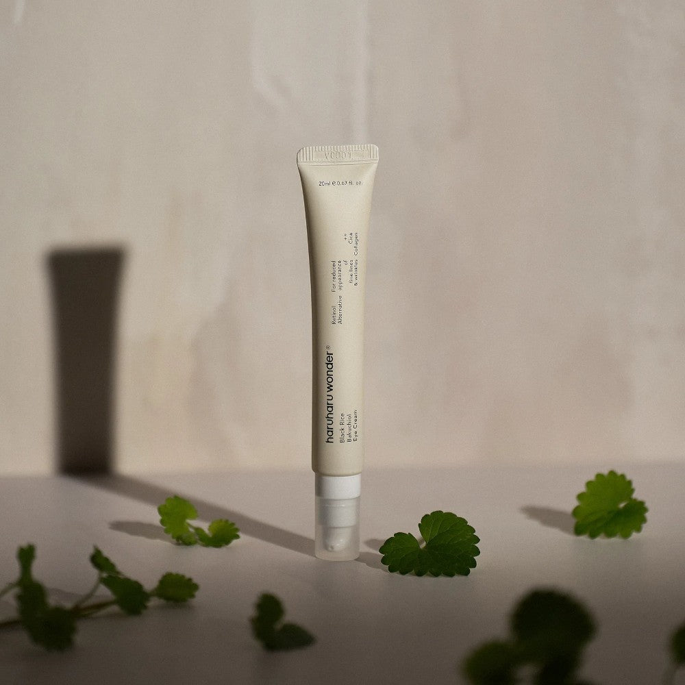 Skin TOGO Haruharu WONDER Black Rice Bakuchiol Eye Cream in a beige tube with green leaves on a neutral background