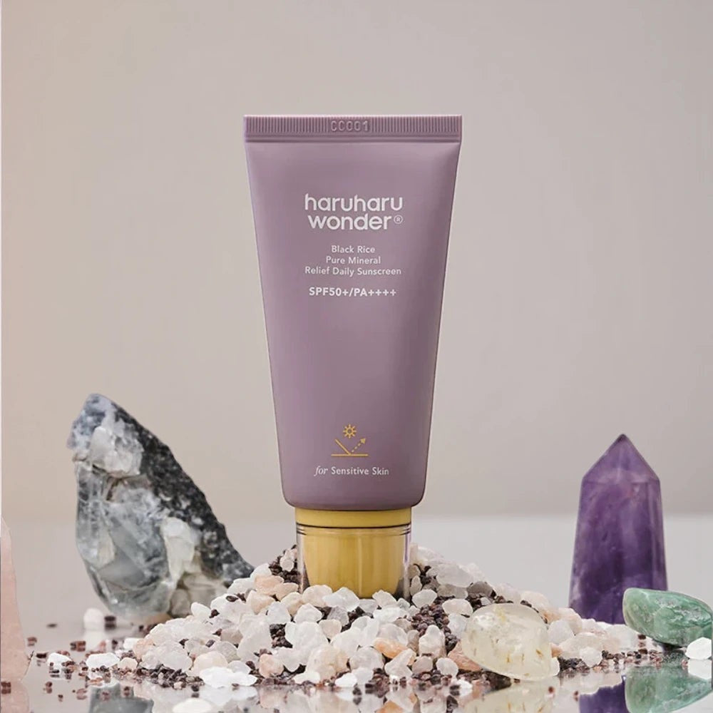 Skin TOGO Haruharu WONDER Black Rice mineral sunscreen tube in a purple bottle with crystals on a reflective surface.