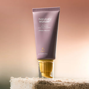 Skin TOGO Haruharu WONDER Black Rice mineral sunscreen in a mauve tube with a yellow cap on a textured stone base.