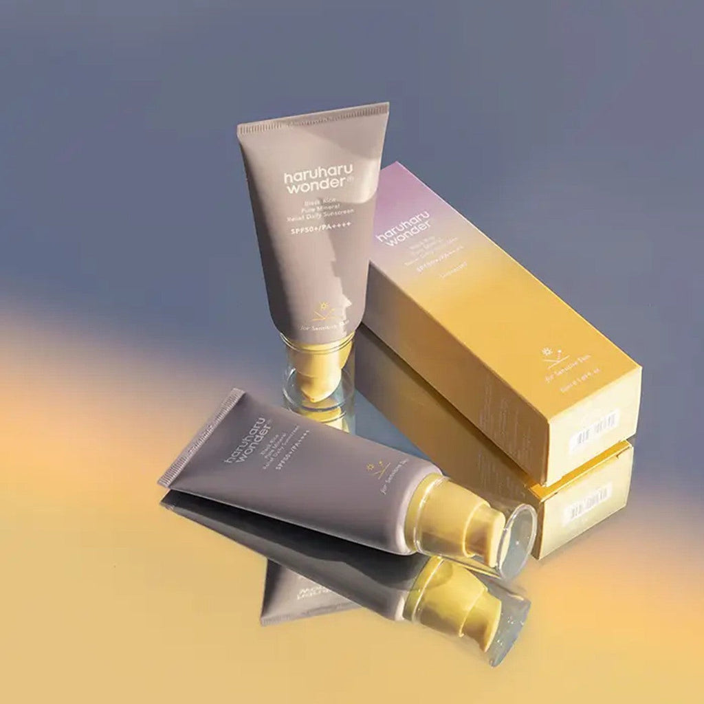 Skin TOGO Haruharu WONDER Black Rice mineral sunscreen tubes and packaging box on a reflective surface.