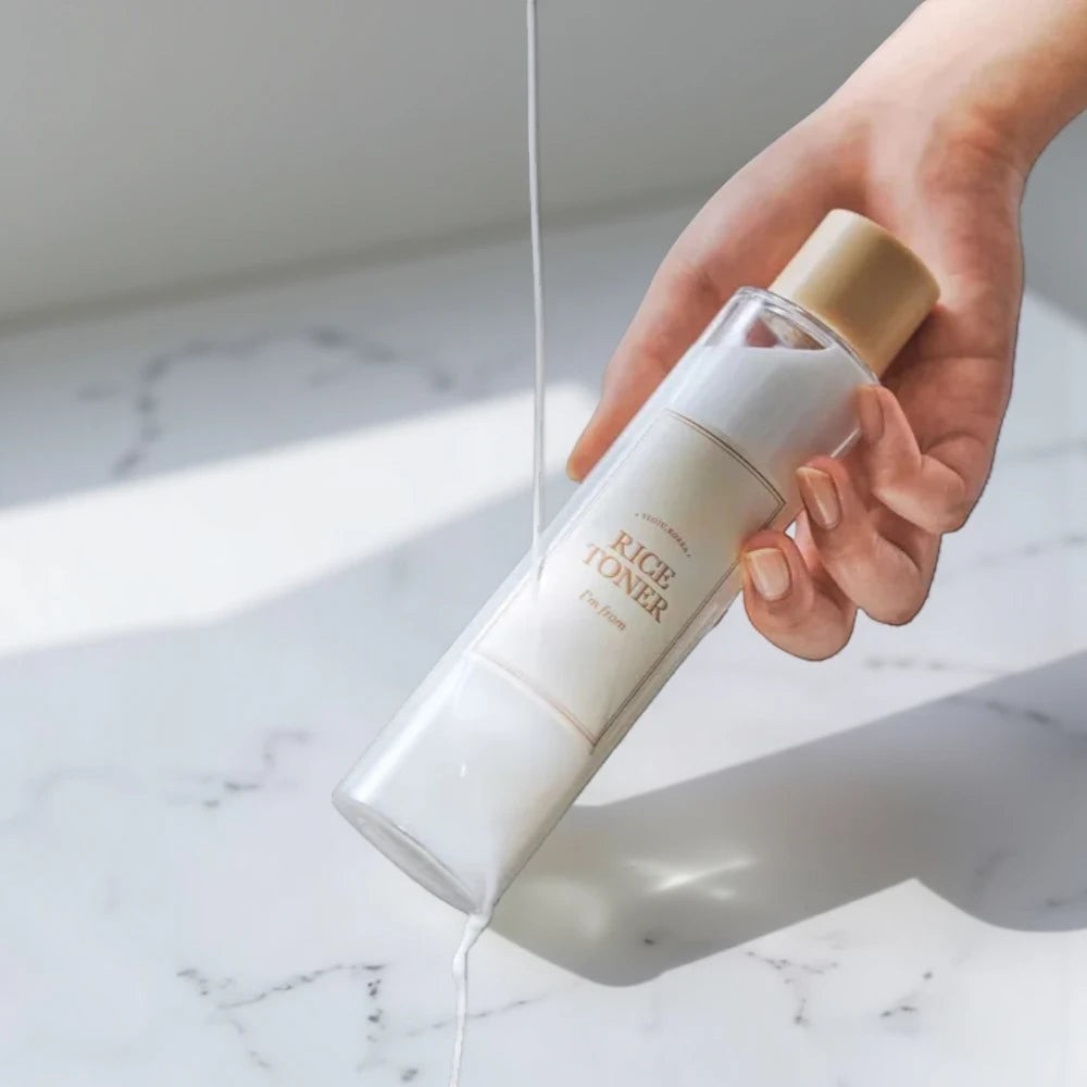 Skin TOGO I'm from Rice Toner with milky texture being poured from a clear bottle held in a hand
