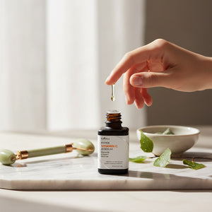 Skin TOGO Isntree Hyper Vitamin C23 serum bottle with a hand applying a drop, set on a marble surface with a roller.