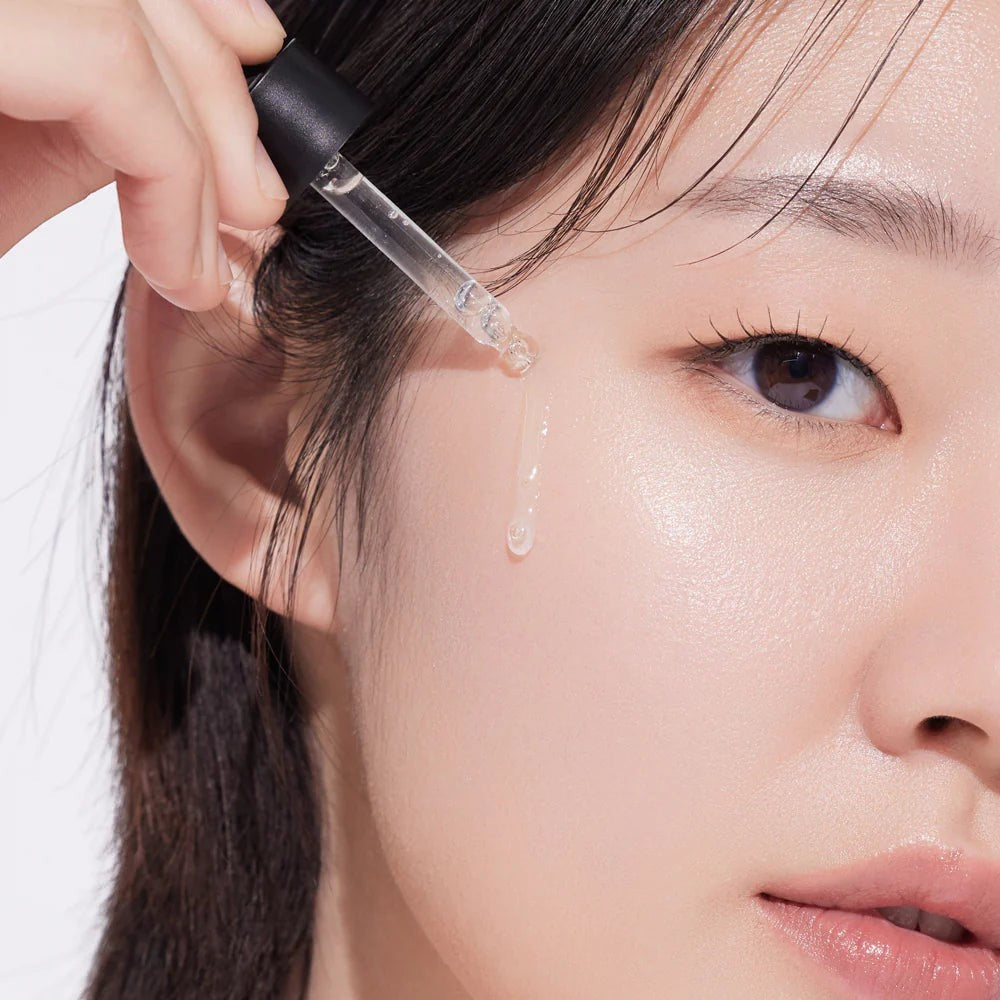 Skin TOGO Isntree Hyper Vitamin C23 serum being applied with a dropper to a woman's glowing, clear skin