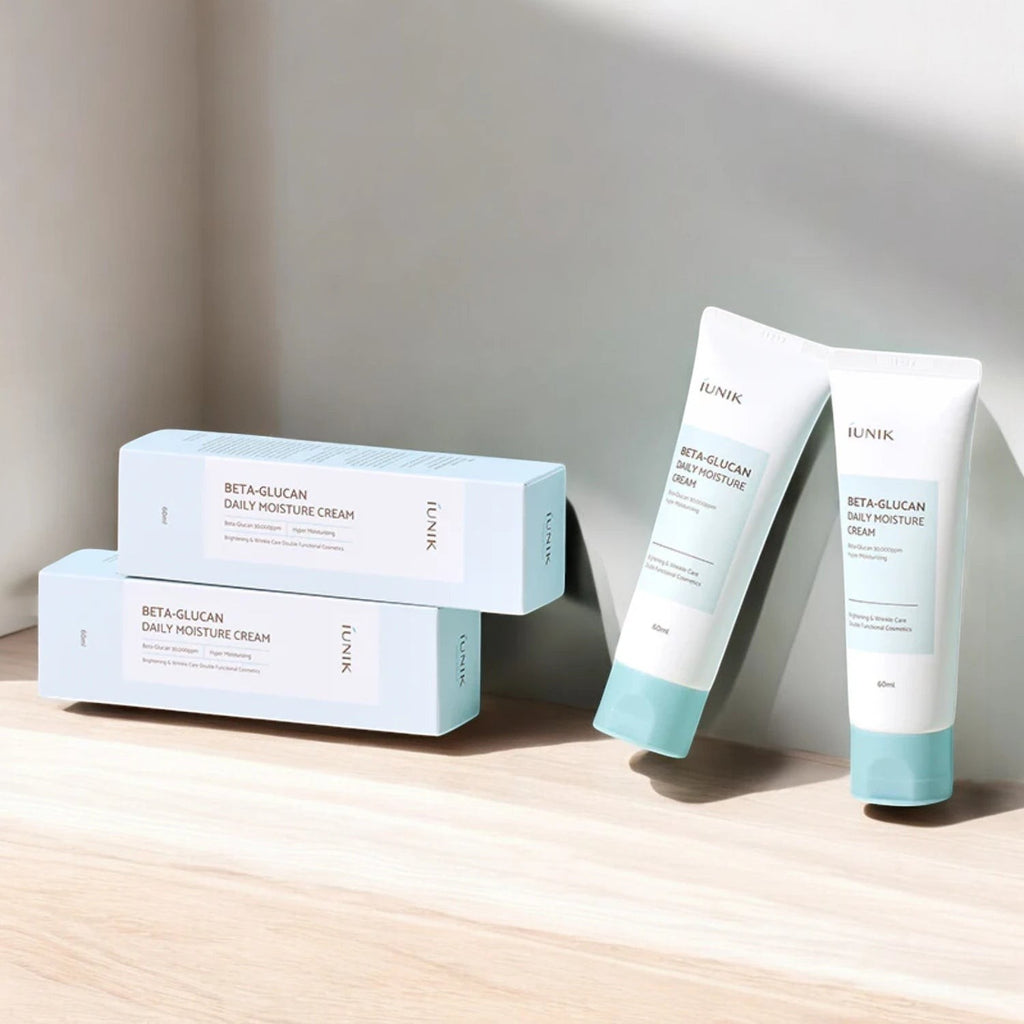 Skin TOGO iUNIK Beta Glucan Daily Moisture Cream tubes and boxes on a wooden surface with soft natural lighting.