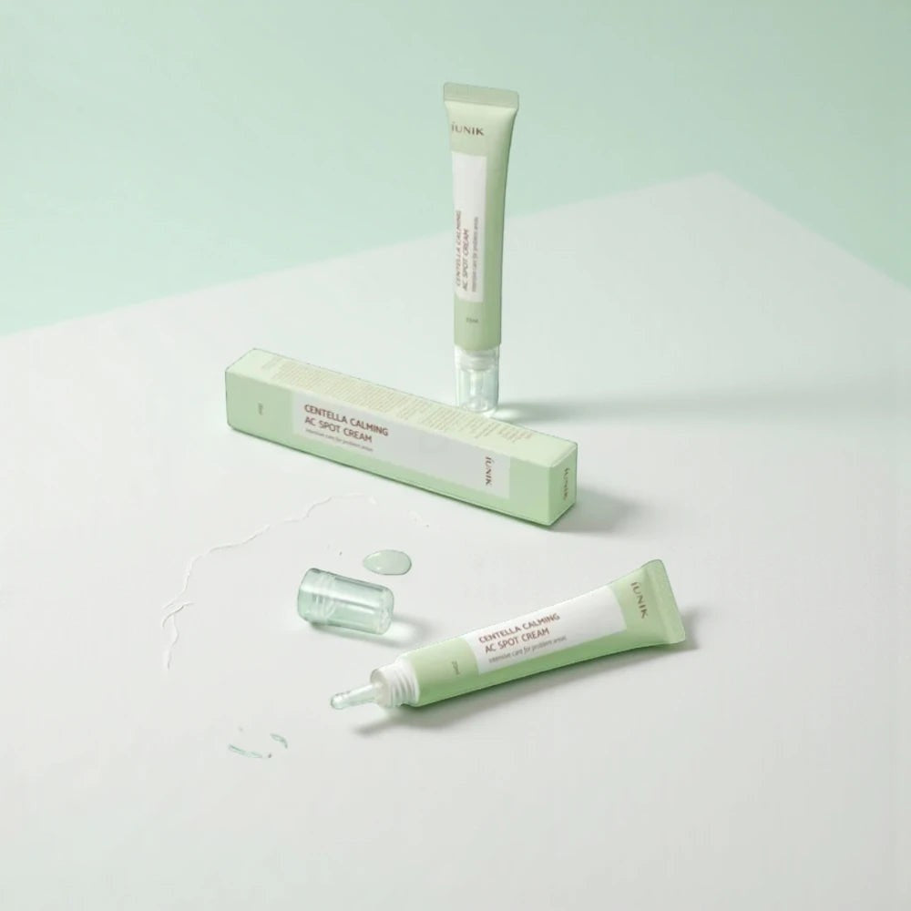 Skin TOGO iUNIK Centella Calming AC Spot Cream tubes and packaging on a light green surface for acne treatment.