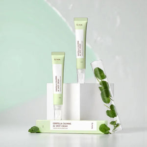 Skin TOGO iUNIK Centella Calming AC Spot Cream tubes with Centella Asiatica leaves in a glass test tube on display.