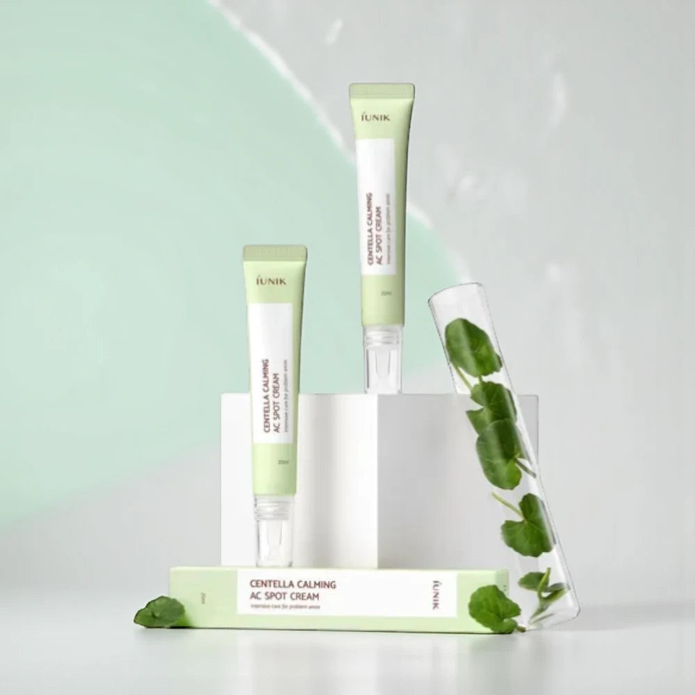 Skin TOGO iUNIK Centella Calming AC Spot Cream tubes with Centella Asiatica leaves in a glass test tube on display.