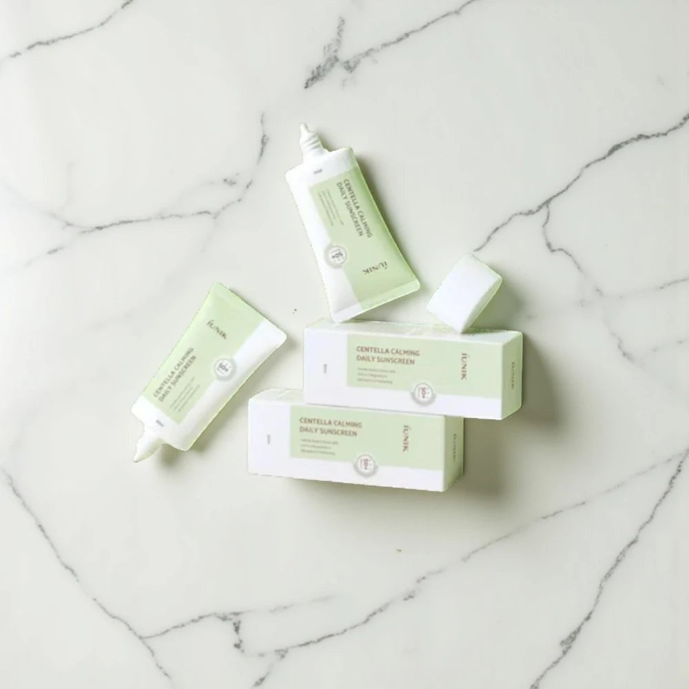 Skin TOGO iUNIK Centella Calming Sun Cream tubes and boxes on a white marble surface