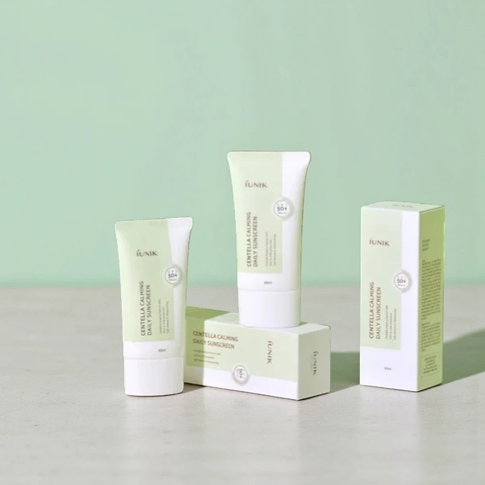 Skin TOGO iUNIK Centella Calming Sun Cream tubes and packaging on a light surface against a soft green background.