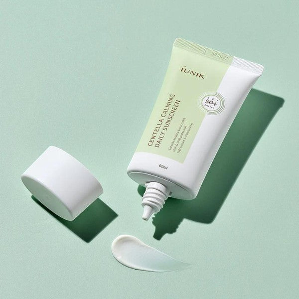 Skin TOGO iUNIK Centella Calming Sun Cream 60ml tube with dispensed white sunscreen on a soft green background.