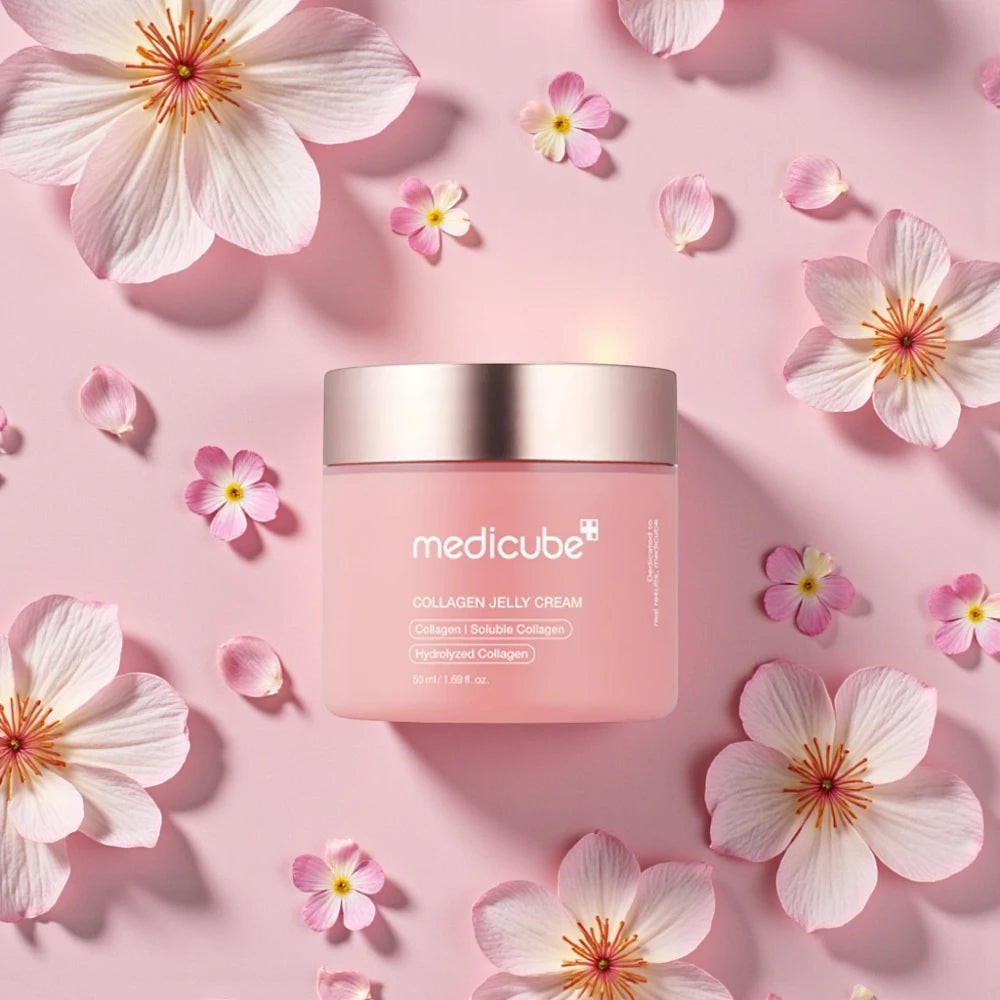 Skin TOGO Medicube Collagen Jelly Cream in a pink jar surrounded by delicate pink flower petals on a soft background.
