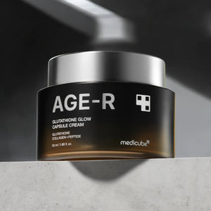 Skin TOGO Medicube AGE-R Glutathione Glow Capsule Cream in a black jar with a silver lid on a stone surface.