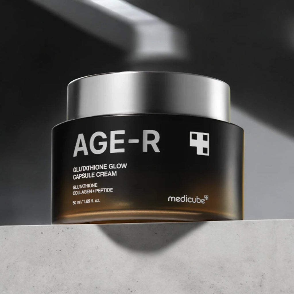 Skin TOGO Medicube AGE-R Glutathione Glow Capsule Cream in a black jar with a silver lid on a stone surface.