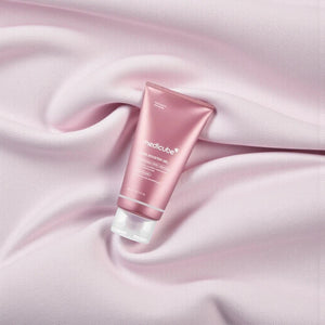Skin TOGO Medicube PDRN Booster Gel in a pink tube resting on soft, draped light pink fabric.