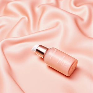 Skin TOGO Medicube Triple Collagen Serum bottle in a soft pink peach glass container on draped satin fabric