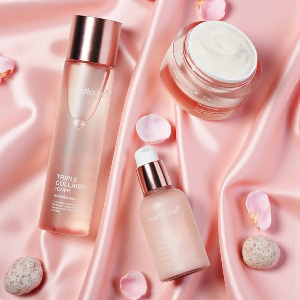 Skin TOGO Medicube Triple Collagen skincare set including toner, serum, and cream on pink satin fabric with petals.