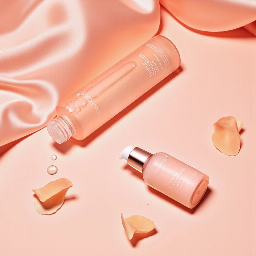 Skin TOGO Medicube Triple Collagen Toner and serum set on a soft peach satin background with scattered rose petals.