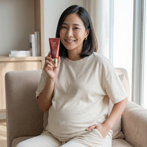 Skin TOGO model holding Missha M Perfect Cover BB Cream in shade #29 Caramel Beige while sitting on a beige sofa.