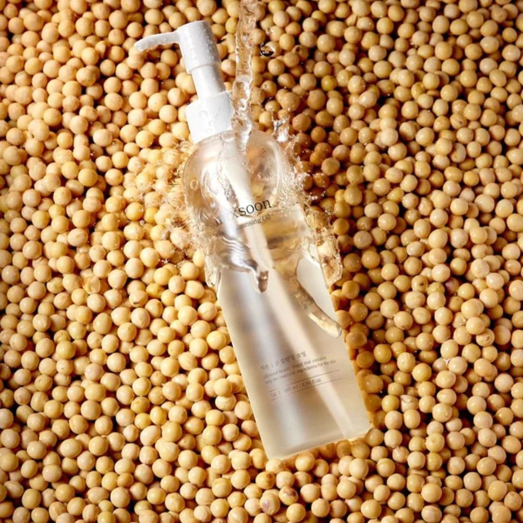 Skin TOGO Mixsoon Bean Cleansing Oil bottle with water splash effect, surrounded by raw soybeans for skincare.