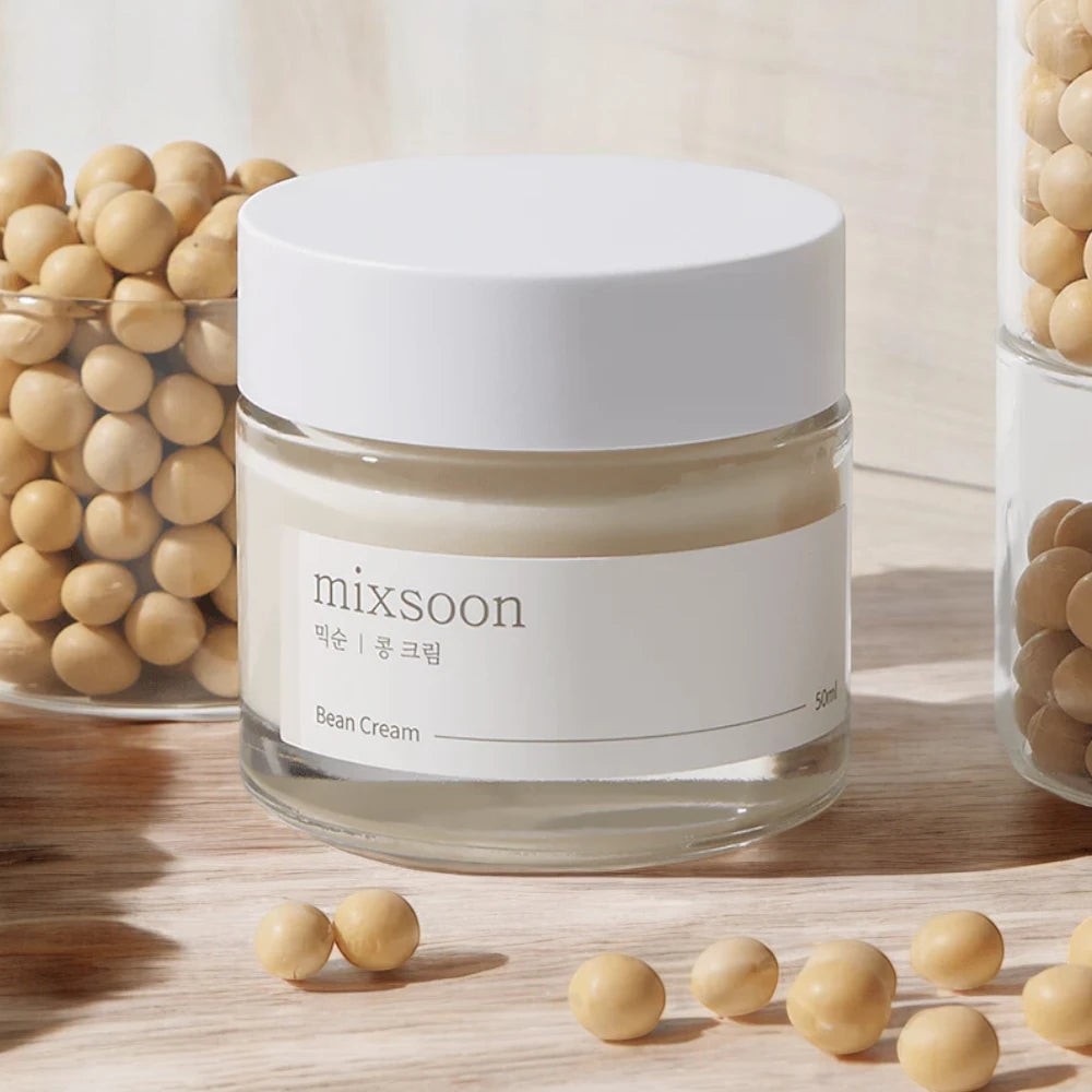 Skin TOGO Mixsoon Bean Cream in a glass jar surrounded by dried soybeans on a light wooden surface.