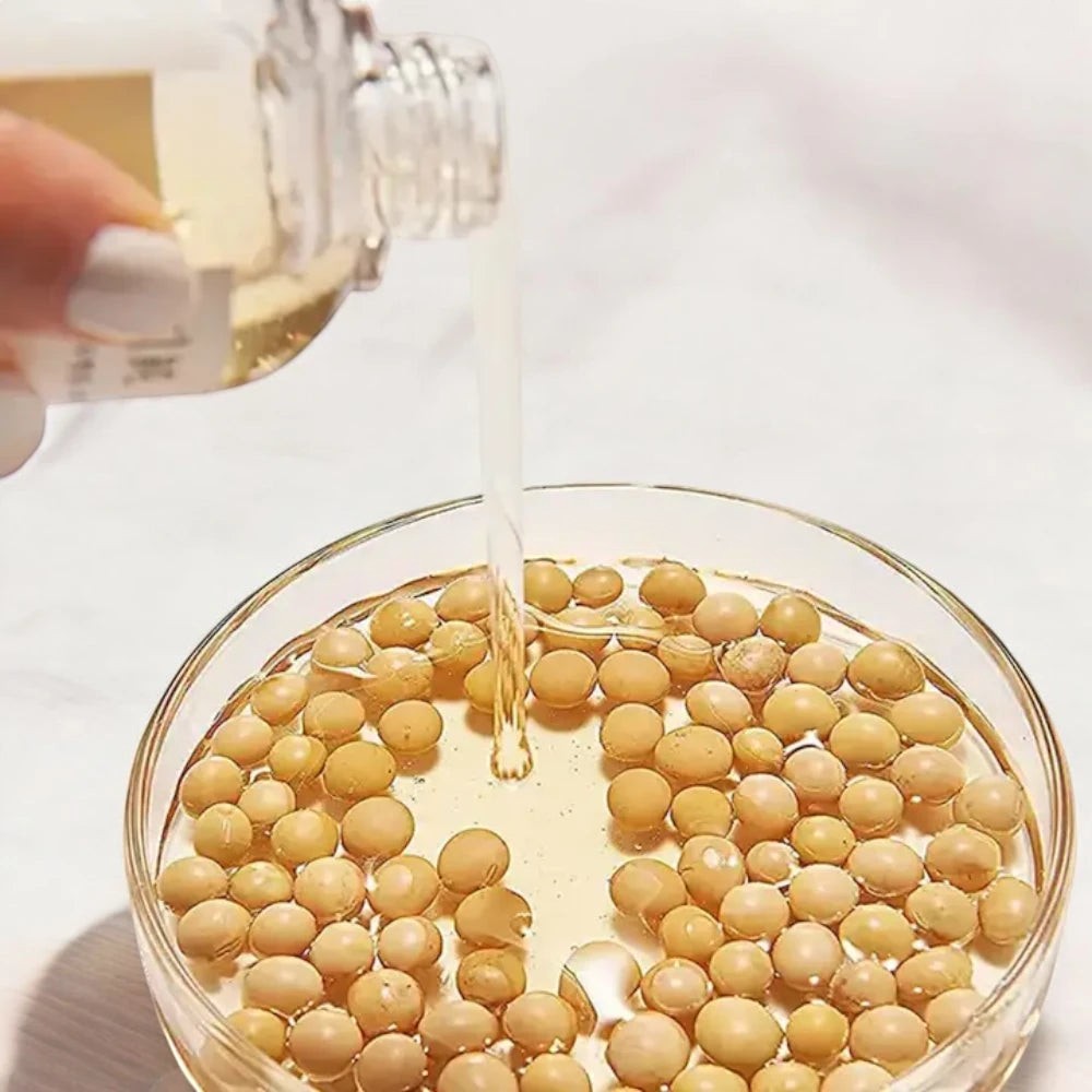 Skin TOGO Mixsoon Bean Essence pouring over a glass dish filled with natural soybeans for skin nourishment.