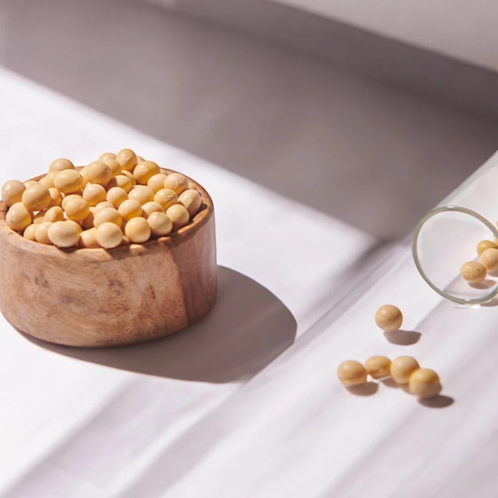 Skin TOGO Mixsoon Bean Essence featuring a wooden bowl filled with soybeans and scattered beans on a white surface