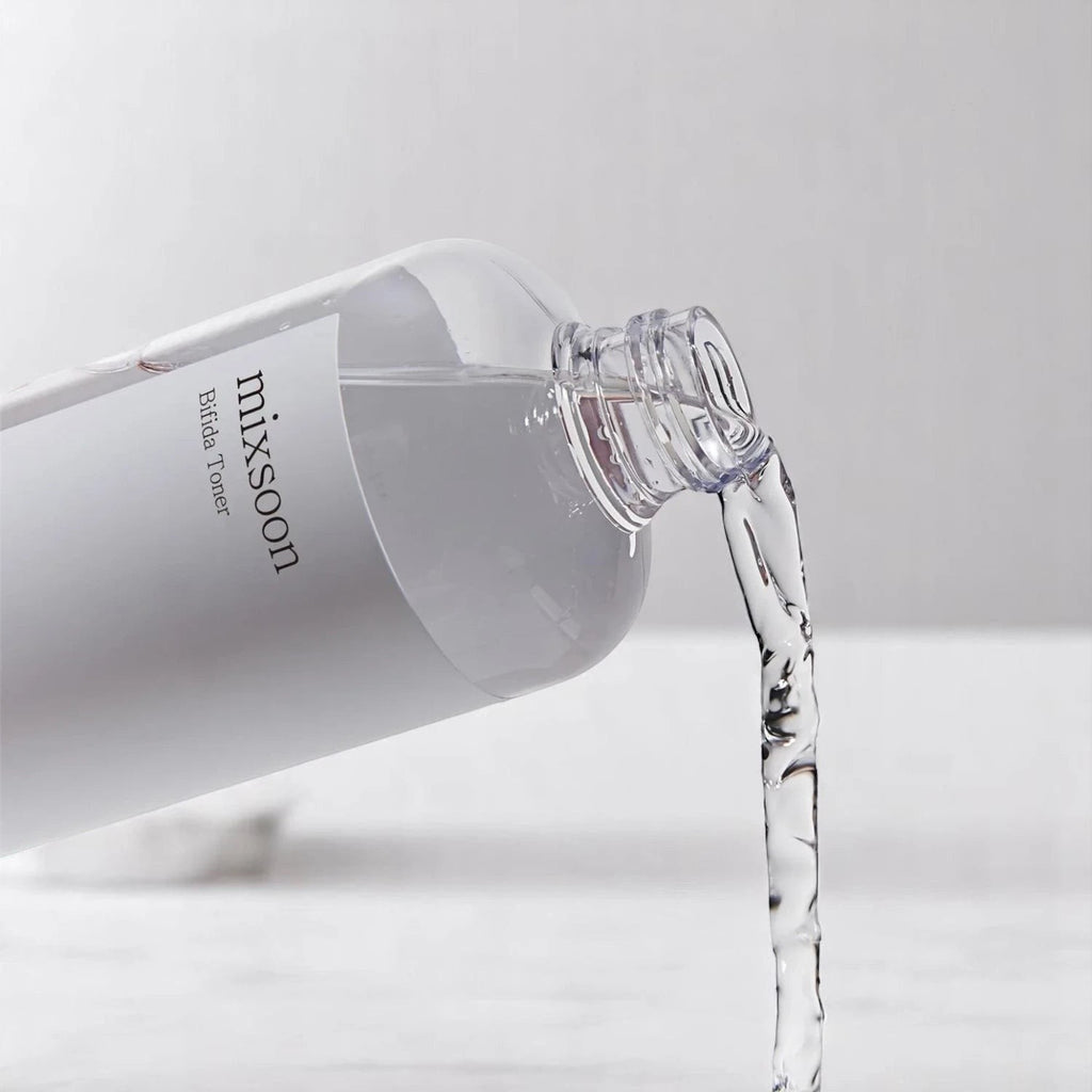 Skin TOGO Mixsoon Bifida Toner pouring from a clear bottle, showcasing its lightweight, watery texture for skin barrier.