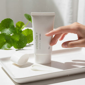 Skin TOGO Mixsoon Centella Sun Cream in a white tube with a dollop of cream on a tray next to fresh centella leaves