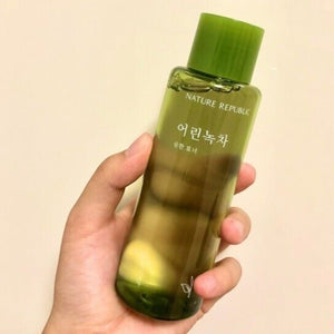 Skin TOGO hand holding a bottle of NATURE REPUBLIC Young Green Tea Mild Toner with a clear green liquid formula.