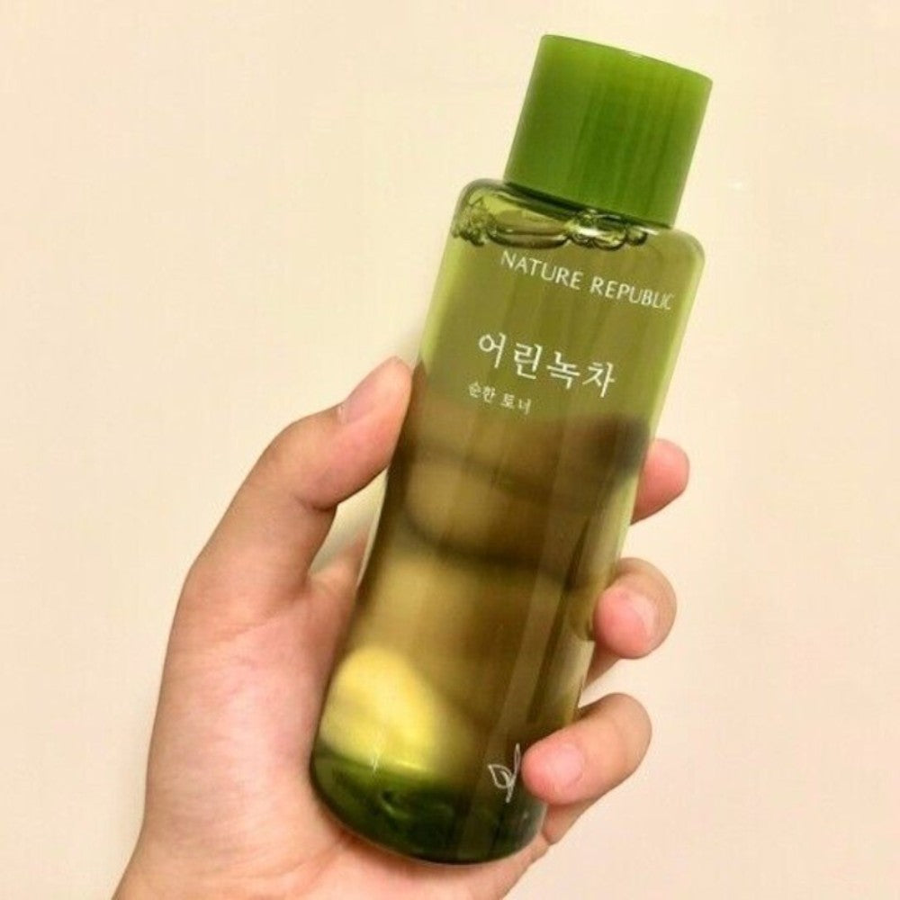 Skin TOGO hand holding a bottle of NATURE REPUBLIC Young Green Tea Mild Toner with a clear green liquid formula.