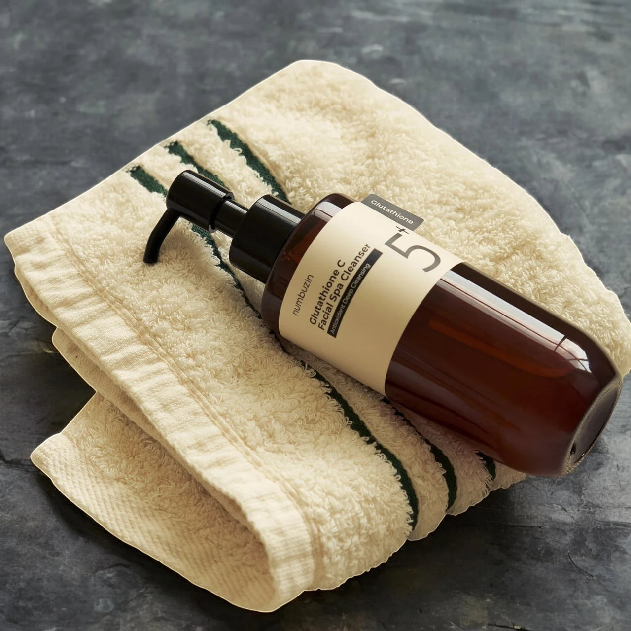 Skin TOGO Numbuzin No.5+ Glutathione Vitamin Facial Spa Cleanser bottle resting on a folded cream-colored towel.