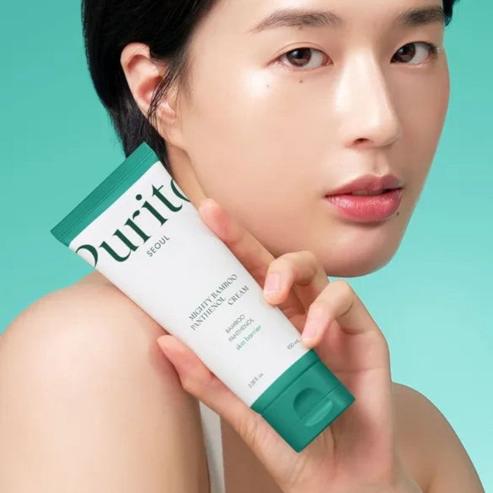 Skin TOGO model holding a white Purito Mighty Bamboo Panthenol Cream tube against a soft green background.