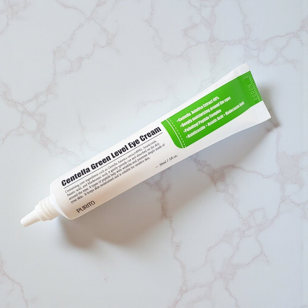 Skin TOGO Purito Centella Green Level Eye Cream tube on a white marble surface, featuring green and white packaging.