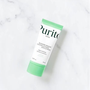 Skin TOGO Purito Wonder Releaf Centella Daily Sun Cream in a white tube with a light green cap on a marble surface.