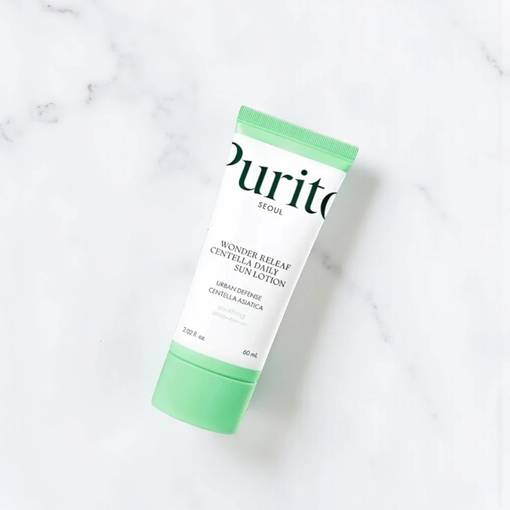 Skin TOGO Purito Wonder Releaf Centella Daily Sun Cream in a white tube with a light green cap on a marble surface.