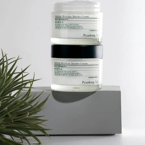 Skin TOGO Pyunkang Yul Calming Moisture Barrier Cream jars stacked on a grey pedestal with a small plant nearby.